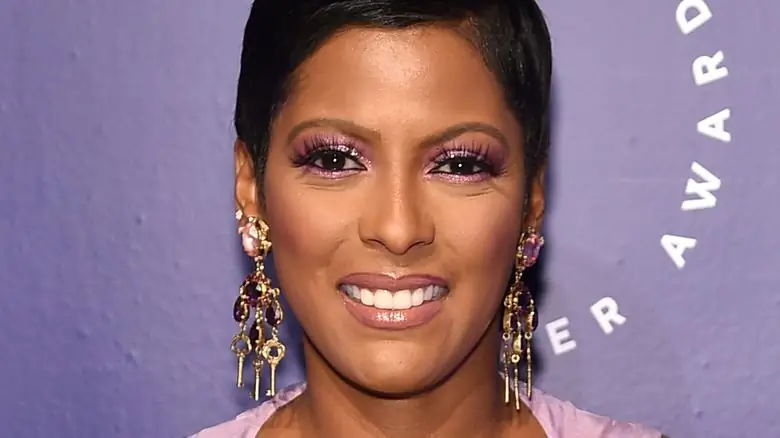 Tamron Hall перед фиолетовой стеной улыбается Tamron Hall перед фиолетовой стеной улыбается