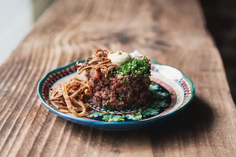 Fête's Steak Tartare: говядина ранчо Куаайна, телятина махики, беарнез-айоли, хрустящий лук-шалот, зеленый лук и тосты с маслом из анчоусов Fête's Steak Tartare: говядина ранчо Куаайна, телятина махики, беарнез-айоли, хрустящий лук-шалот, зеленый лук и тосты с маслом из анчоусов